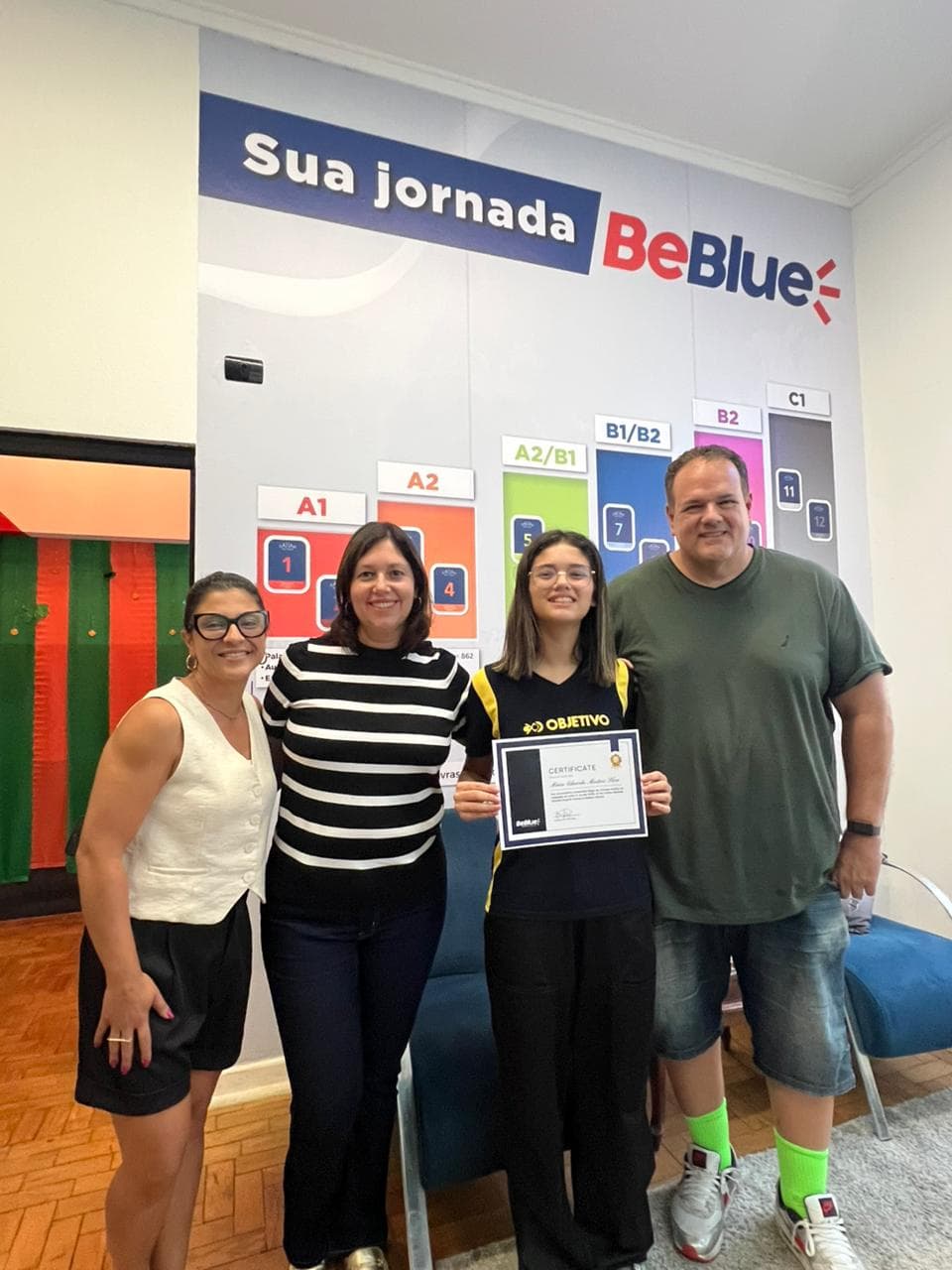 Maria Eduarda, aluna da BeBlue School, segurando o certificado ao lado da família e da equipe da escola